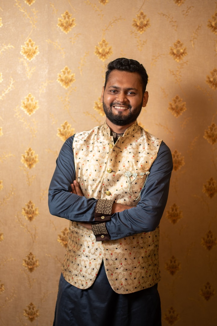 Uomo sorridente con indumenti tradizionali su sfondo dorato decorativo.