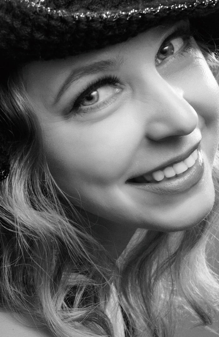 Ritratto in bianco e nero di una donna sorridente con cappello.